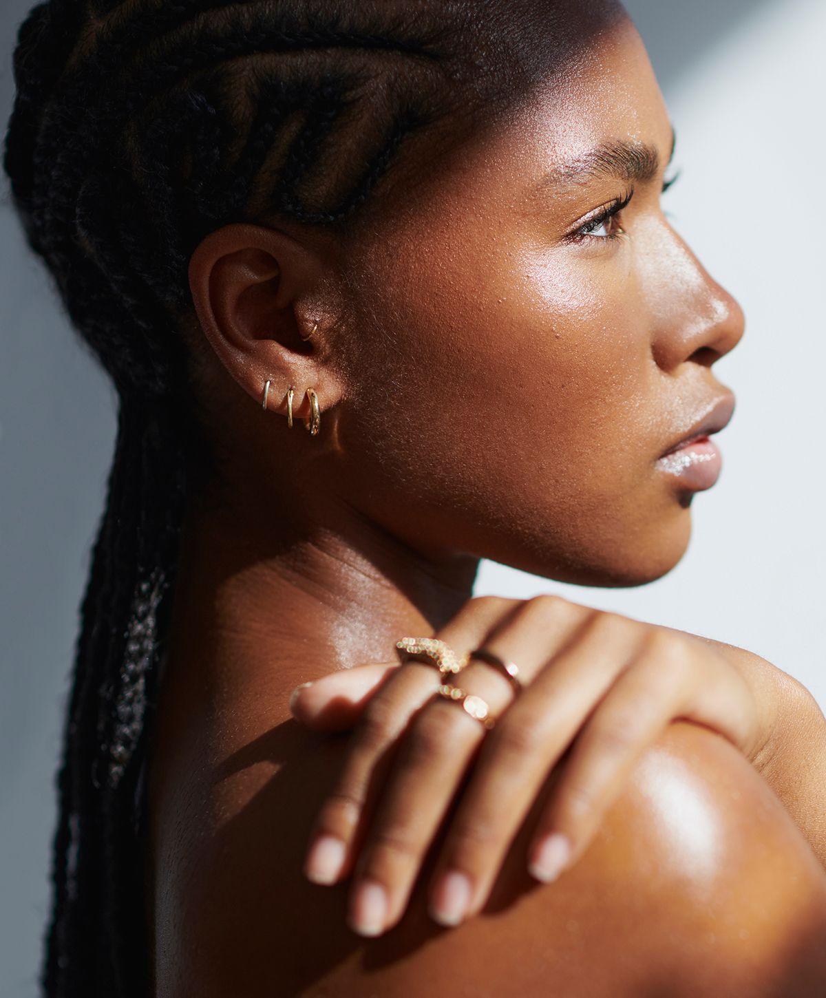 Woman with braided hair displaying gold jewelry.