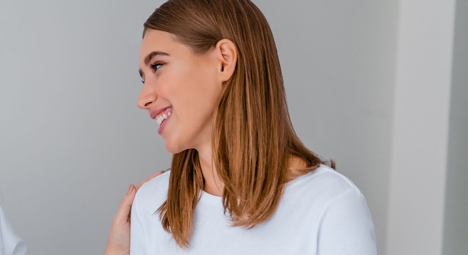 Smiling woman with long hair in white shirt.