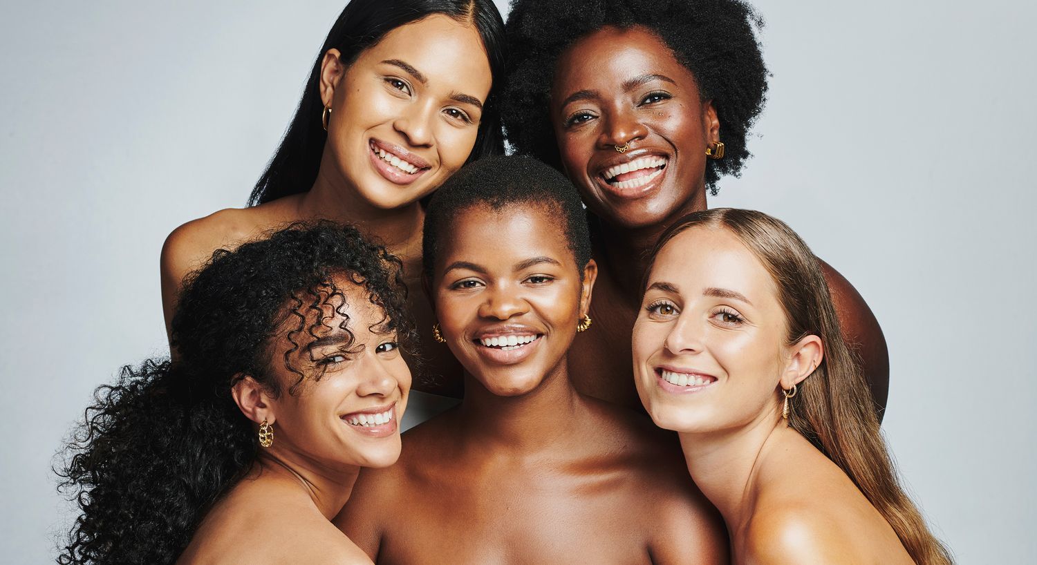 Diverse group of smiling women posing together.