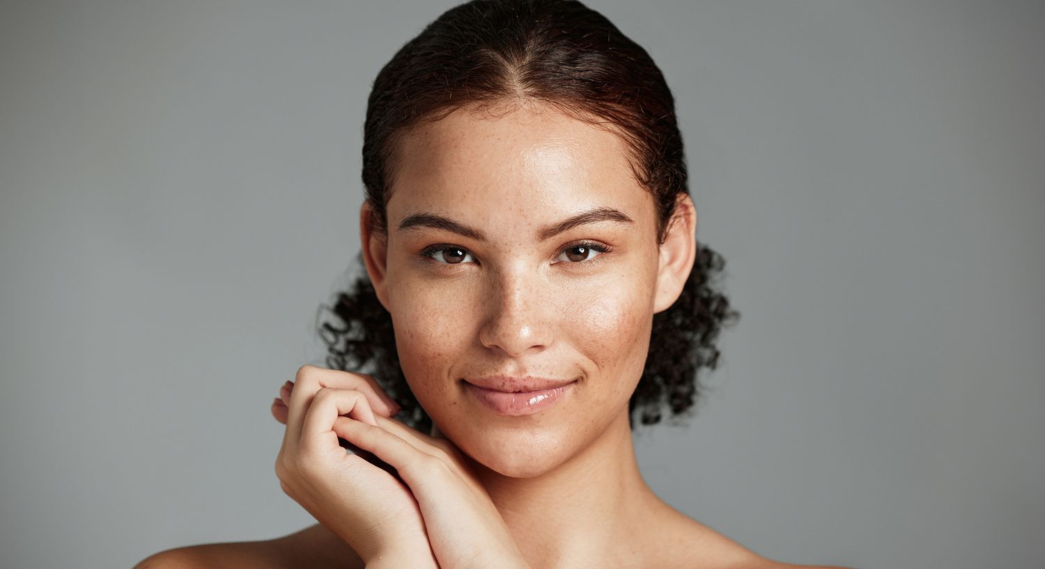 Smiling person with curly hair and freckled skin.
