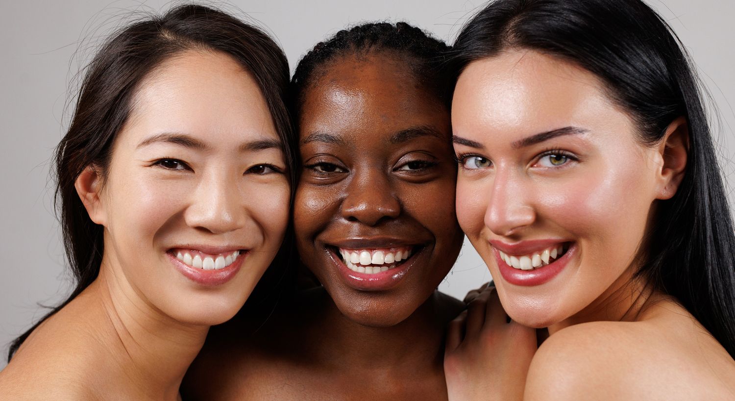 Three smiling women with diverse backgrounds.